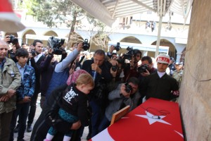 CENAZE NAMAZI ÖNCESİ ŞEHİT EŞİ EBRU YAKINLARIN DESTEĞİYLE EŞİNİN TÜRK BAYRAĞINA SARILI TABUTUNA UZUN SÜRE BAKARAK, TERÖRE İNAT DİMDİK AYAKTA DURDU. HER ŞEYDEN HABERSİZ BABASININ FOTOĞRAFINI ÖPEN 1 YAŞINDAKİ BEGÜM’ÜN BU GÖRÜNTÜSÜ DUYGU DOLU ANLARIN YAŞANMASINA NEDEN OLDU. (ALİ KEKLİK - MUHAMMET ÖZER/KAHRAMANMARAŞ-İHA)